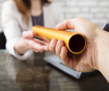 One hand passing a relay baton to another across a desk, symbolizing business succession