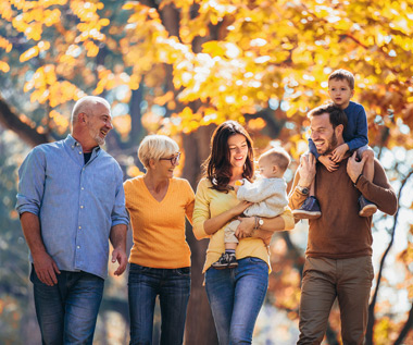 Three generations of a family walking together through an autumn park